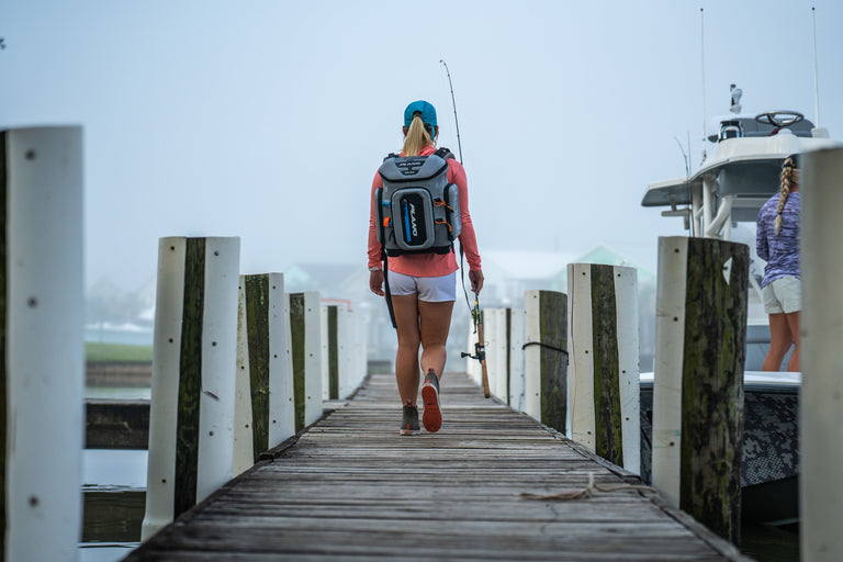 woman on a dock with a plano fishing backpack and fishing rod
